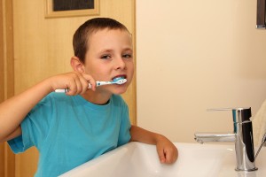 Six years old boy cleaning tooth in the bathroom.