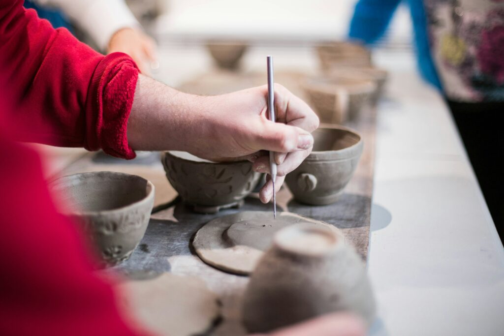 Person carving into wet clay at a pottery studio