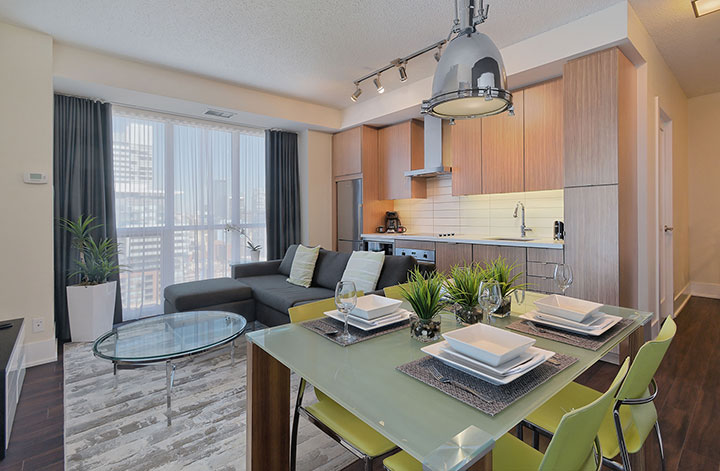 A modern living room, kitchen, and dining area in a suite at 300 Front St.