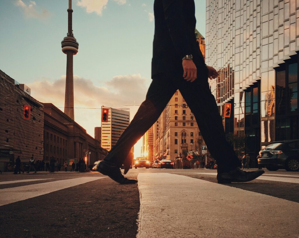 Person in suit walking across the road downtown Toronto.