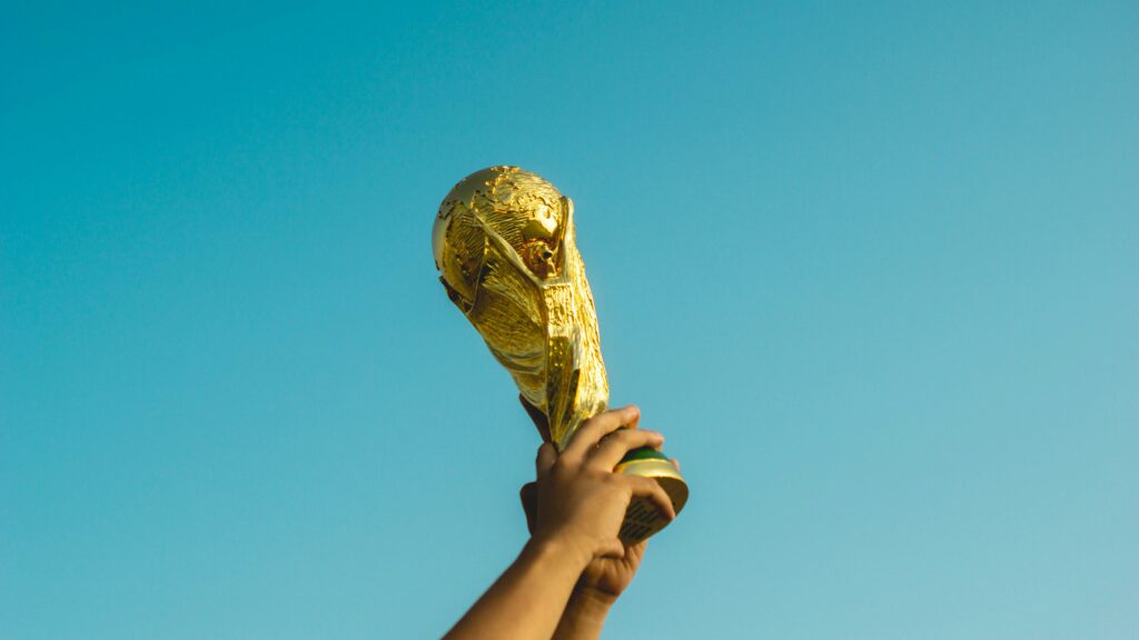 Person holding a World Cup trophy against a blue sky.