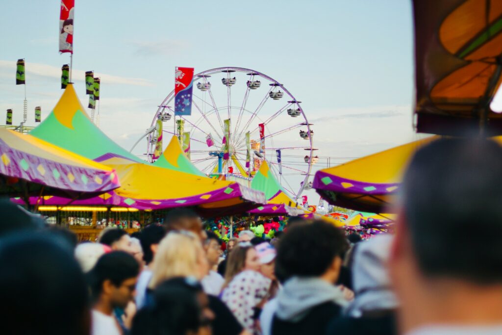 Photo from a crowd at the CNE of colourful tents and a ferris wheel.