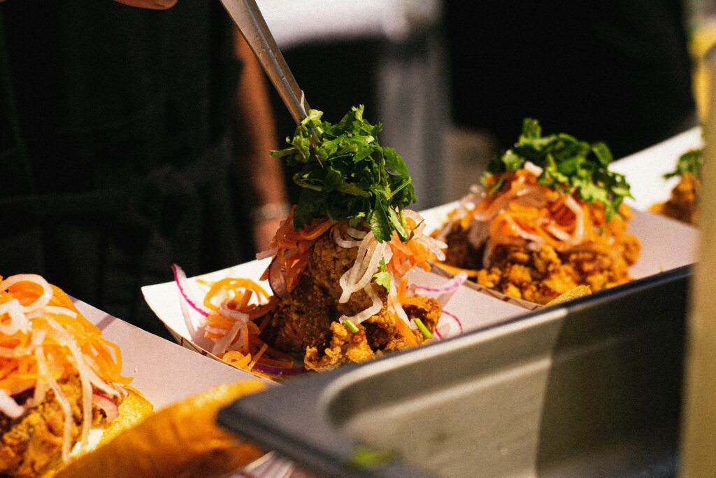 Karaage fried chicken topped with pickled veggies in individual paper bowls.