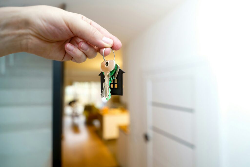 An open apartment door with a person’s hand holding keys in the doorway.